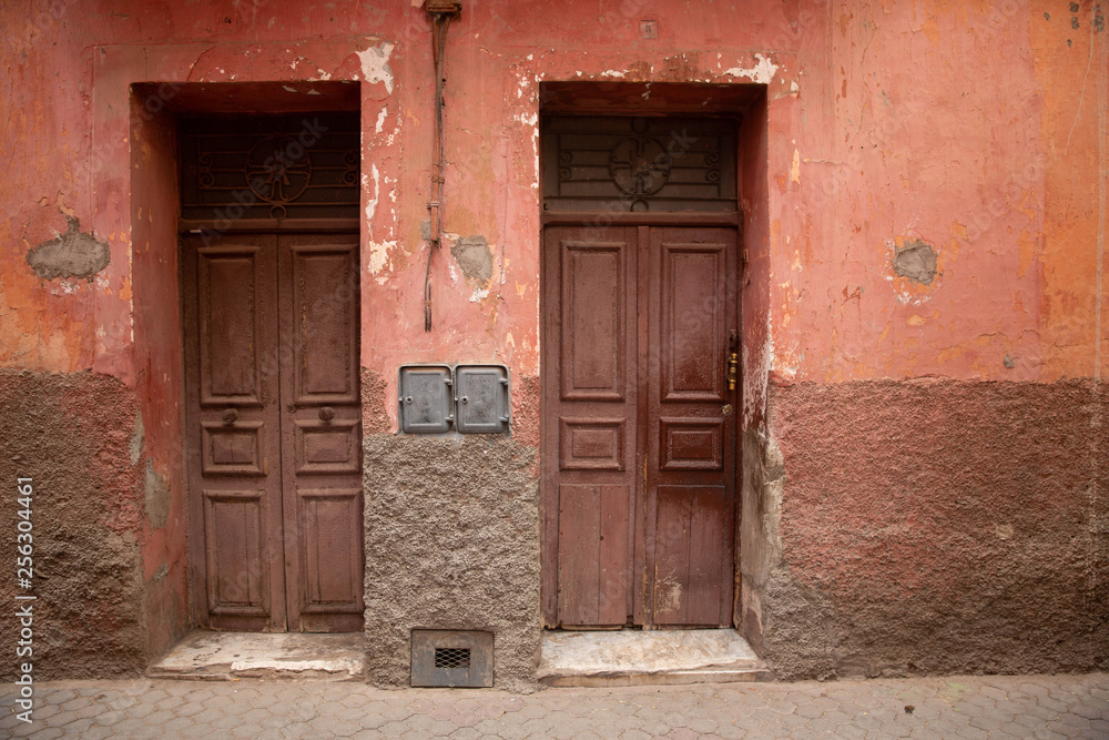 Beautiful old street of Marrakech with red buildings and old doors, Morocco.