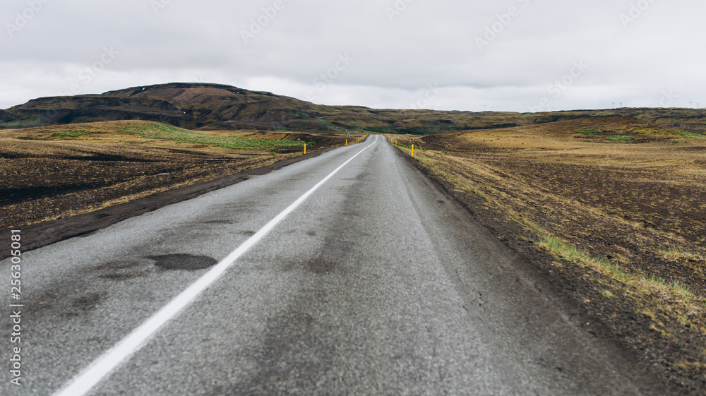 The road between the mountains and the hills. Asphalt road in Iceland. The road is in the field.