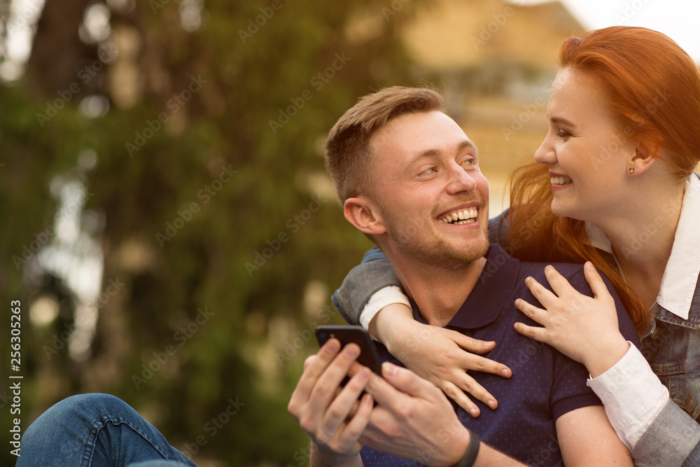 Fototapeta premium College couple using digital gadgets on campus