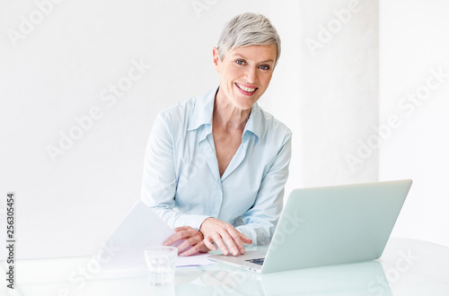 Portrait of smiling mature businesswoman working on laptop
