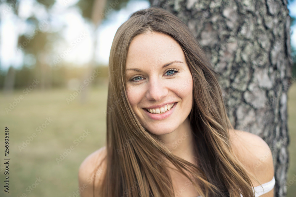 Portrait of smiling young woman leaning against tree trunk Portrait of smiling young woman leaning against tree trunk