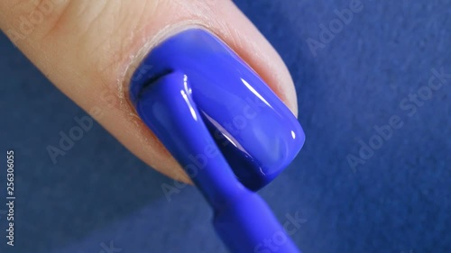 Beautiful manicure process. Nail polish being applied to nail, polish is a blue color.