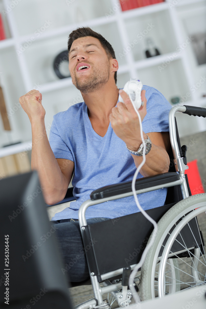 Obraz premium happy man in wheelchair making victory gesture for computer game