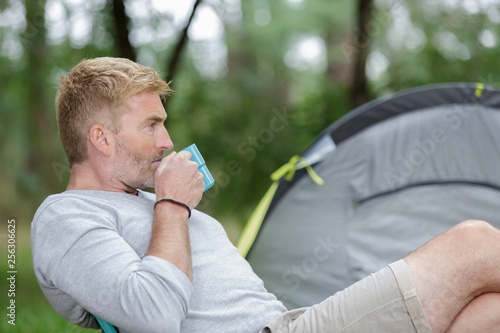 thoughtful man drinking coffee next to his tent