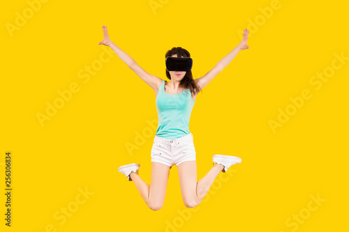 girl in VR glasses of virtual reality is jumping on a yellow background