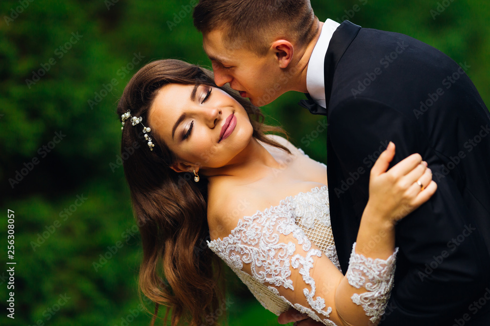 the bride with a beautiful makeup closes her eyes and the groom