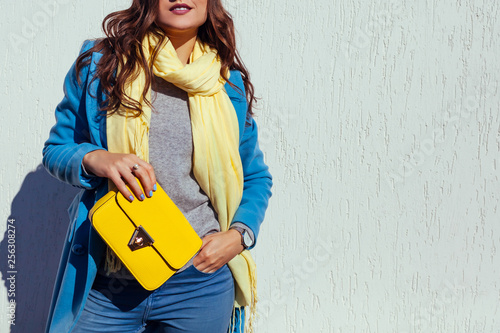 Young woman holding stylish handbag and wearing trendy blue coat. Spring female clothes and accessories. Fashion photo