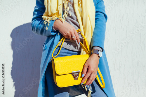 Tableau sur toile Young woman holding stylish handbag and wearing trendy blue coat