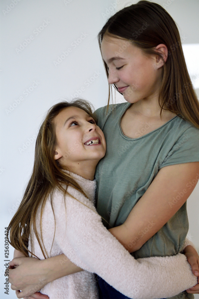 Two happy sisters hugging each other Two happy sisters hugging each other