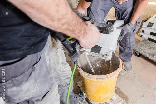 Mixing plaster solution in a bucket, using an electric drill
