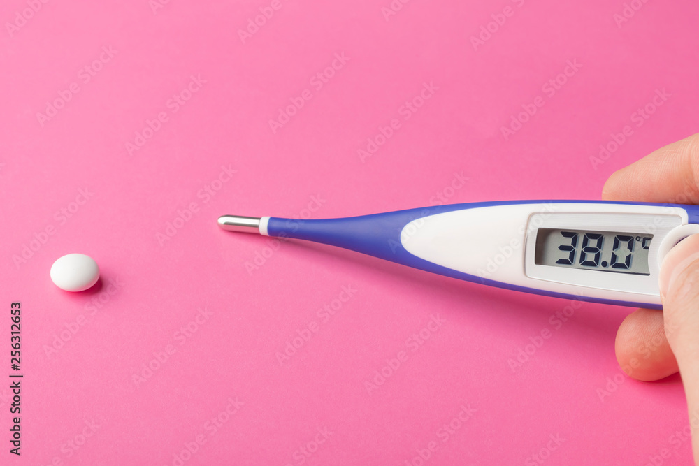 Electronic thermometer and pill on a pink background. High temperature 38  degrees Celsius on display. Stock Photo | Adobe Stock