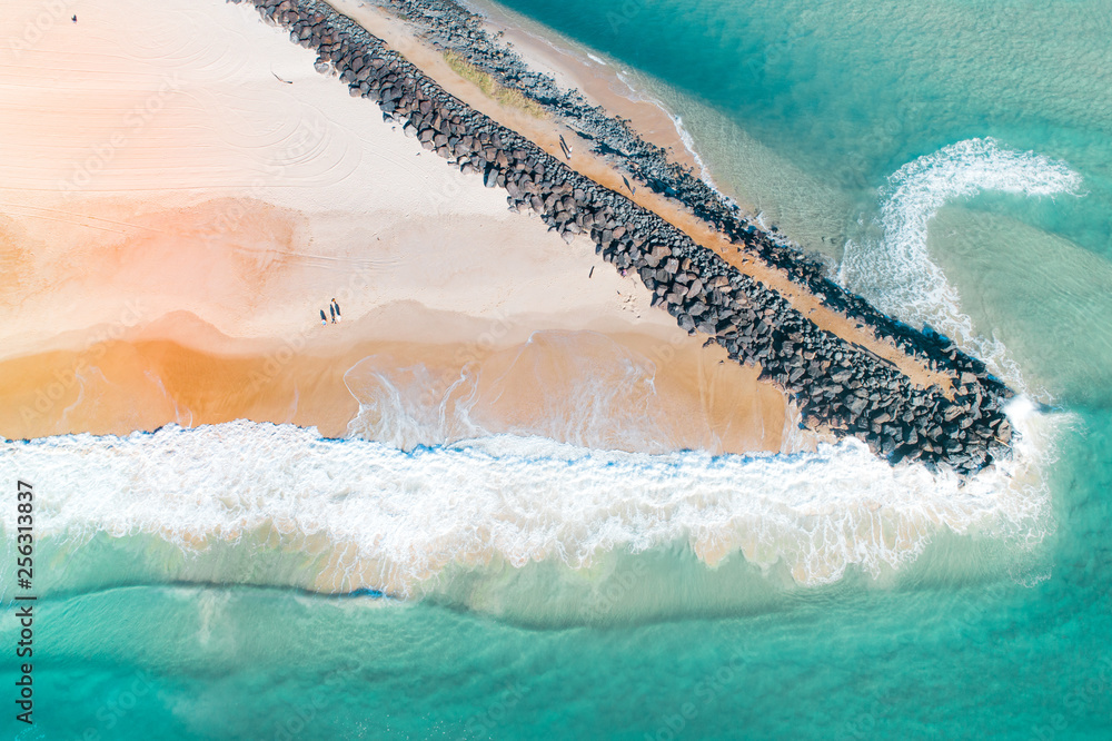 Beautiful aerial shot of a beach with nice sand, blue turquoise water. Top shot of a beach scene with a drone