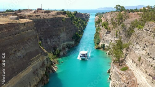 Beautiful scenery of the Corinth Canal in a bright sunny day against a blue sky. Among the rocks floating white ship in turquoise water. Greece photo