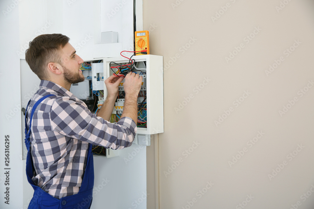 Electrician with tester checking voltage indoors, space for text
