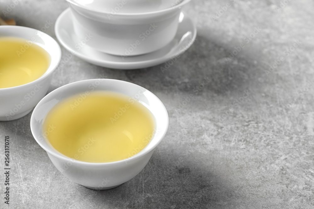 Cups of freshly brewed oolong tea on grey table. Space for text Cups of freshly brewed oolong tea on grey table. Space for text