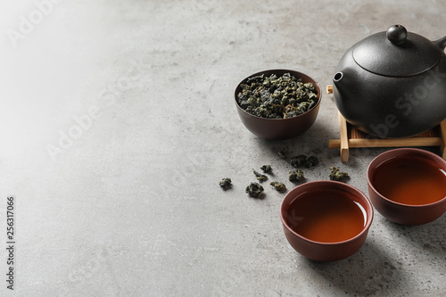 Teapot, cups of Tie Guan Yin oolong and tea leaves on table. Space for text photo