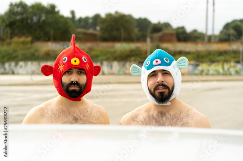 Portrait of shirtless gay couple wearing animal hats outdoors