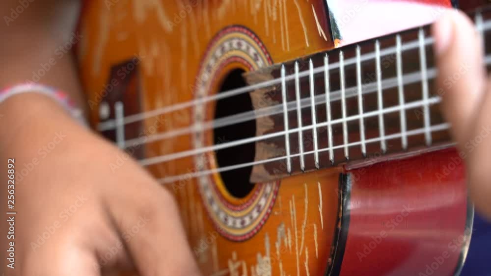 Man musician playing of a acoustic guitar on the street market in Ubud, island Bali, Indonesia. Male hands playing on the strings of a old guitar, close up Man musician playing of a acoustic guitar on the street market in Ubud, island Bali, Indonesia. Male hands playing on the strings of a old guitar, close up