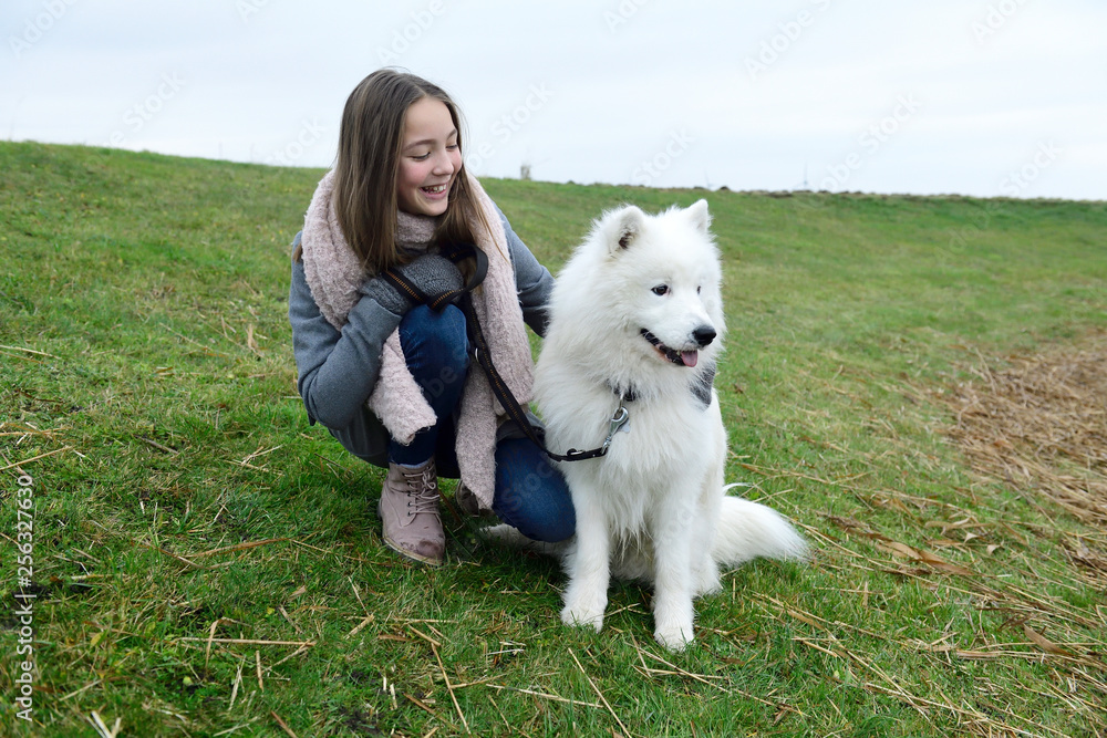 Happy girl crouching on a meadow with her dog Happy girl crouching on a meadow with her dog