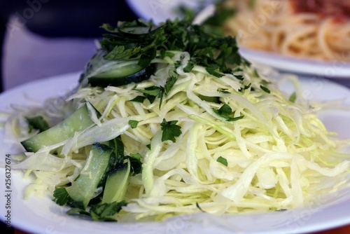 fresh salad of white cabbage and green cucumbers on a plate