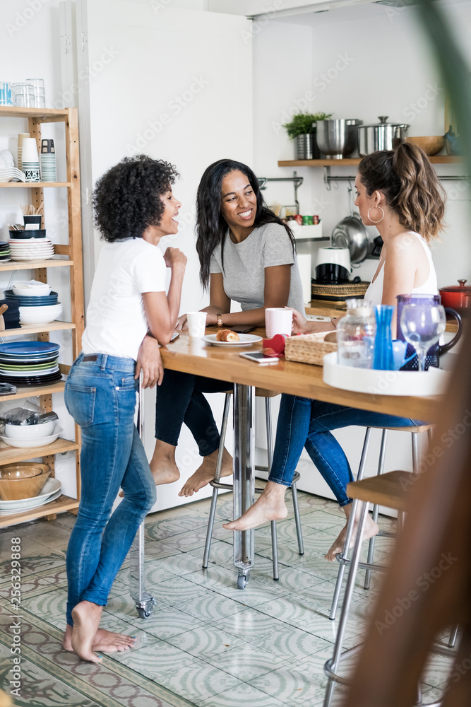 Three happy women socializing at kitchen table at home Three happy women socializing at kitchen table at home