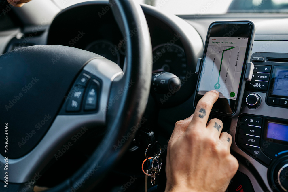 Close-up of man with tattooed hand driving car using cell phone as navigation system Close-up of man with tattooed hand driving car using cell phone as navigation system