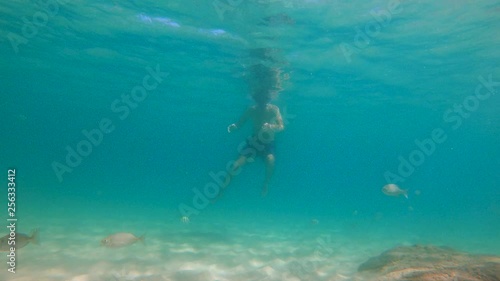 4k Slowmotion shot of young caucasian man snorkeling in a mask and breathing tube in a a beautiful sea with lots of tropical fishes photo