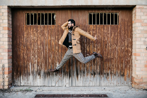 Spain, Igualada, happy man jumping mid-air at rundown wooden gate photo