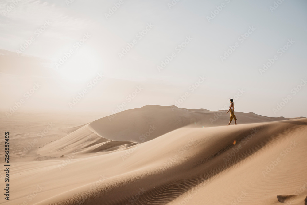 Namibia, Namib, woman on desert dune looking at view Namibia, Namib, woman on desert dune looking at view