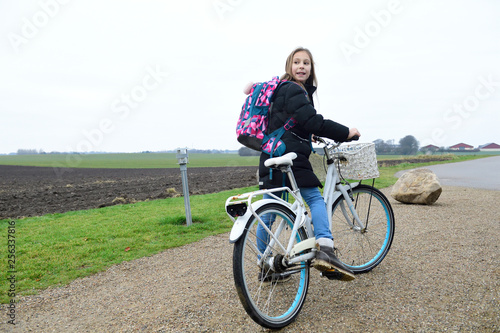 Girl with backpack and bicycle in rural landscape