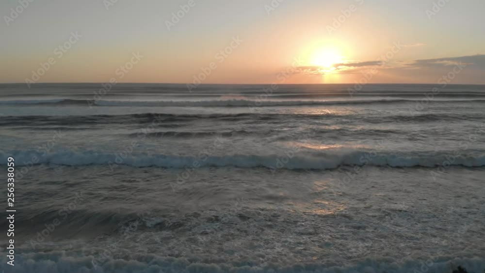 Aerial view circling over a wild ocean with big waves, showing a sunset with clouds Aerial view circling over a wild ocean with big waves, showing a sunset with clouds