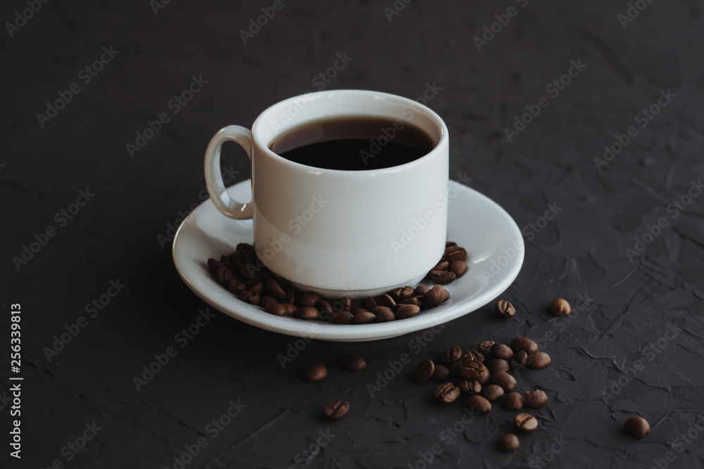 Fototapeta premium White cup of coffee and coffee beans on a dark background