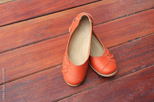 Orange leather female shoes on wood