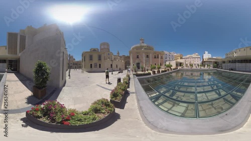 VALENCIA, SPAIN - JULY 15 2016: 360 VR video. People walking near Almoina Archaeological Center. Man tourist (with model release) standing by the old city ruins under the glass photo