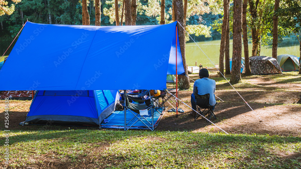 Asian man travel nature camping on the Mountain see the lake in the mist, Camping and tent under the pine forest in sunset at north of Thailand. Asian man travel nature camping on the Mountain see the lake in the mist, Camping and tent under the pine forest in sunset at north of Thailand.