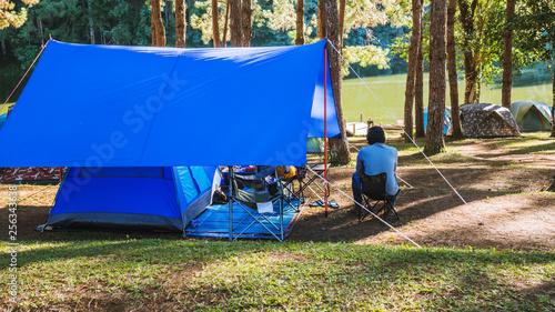 Asian man travel nature camping on the Mountain see the lake in the mist, Camping and tent under the pine forest in sunset at north of Thailand.