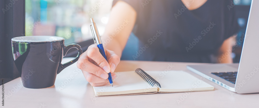 Obraz premium Business woman's hand is writing on a notebook with a pen.