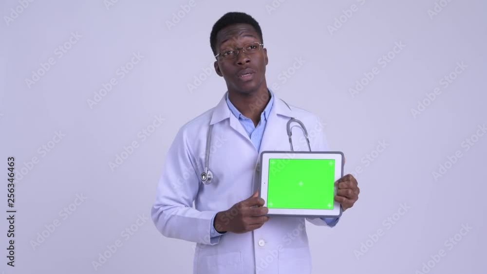 Young happy African man doctor talking while showing digital tablet Young happy African man doctor talking while showing digital tablet