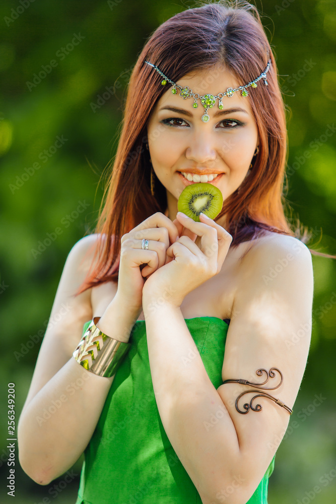 Beautiful young asian woman biting slice of kiwi Beautiful young asian woman biting slice of kiwi