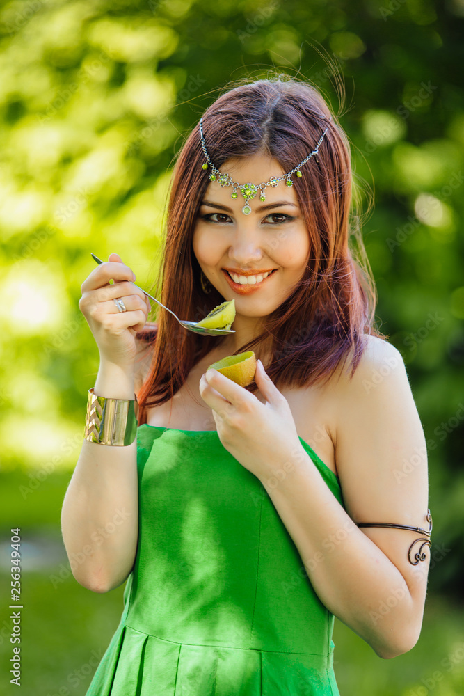 Beautiful young asian woman eating fresh kiwi Beautiful young asian woman eating fresh kiwi