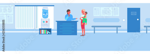 female nurse at reception desk with mother and son patients medicine concept hospital hall interior modern clinic waiting room flat horizontal
