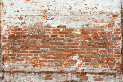 The texture of the old brick wall painted white with peeling paint