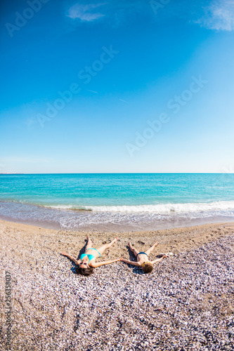 The boy with his mother sunbathe on the beach.