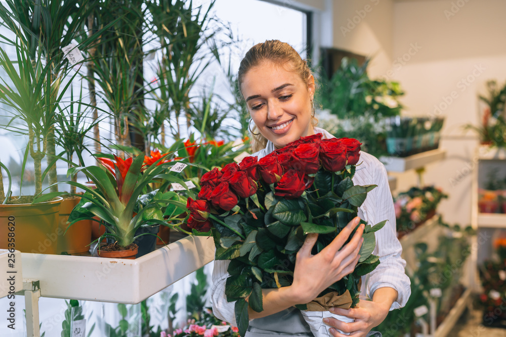 happy woman holding bouquet of roses in flower shop