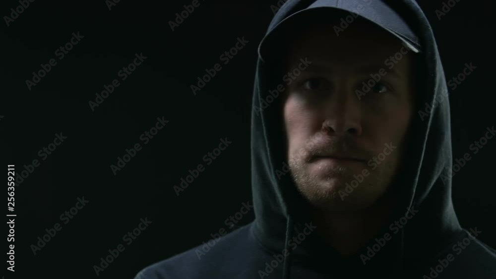 Hooded gang member looking menacingly into camera, preparing mentally for crime Hooded gang member looking menacingly into camera, preparing mentally for crime