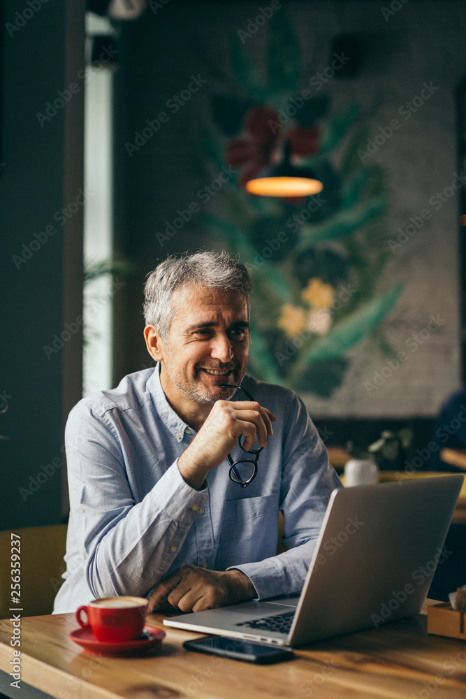 working even on a coffee break. business man using laptop in cafeteria working even on a coffee break. business man using laptop in cafeteria