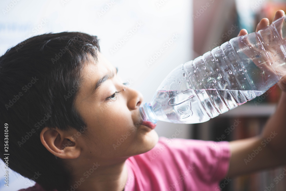 Little boy drinking water in the room with happy face Little boy drinking water in the room with happy face