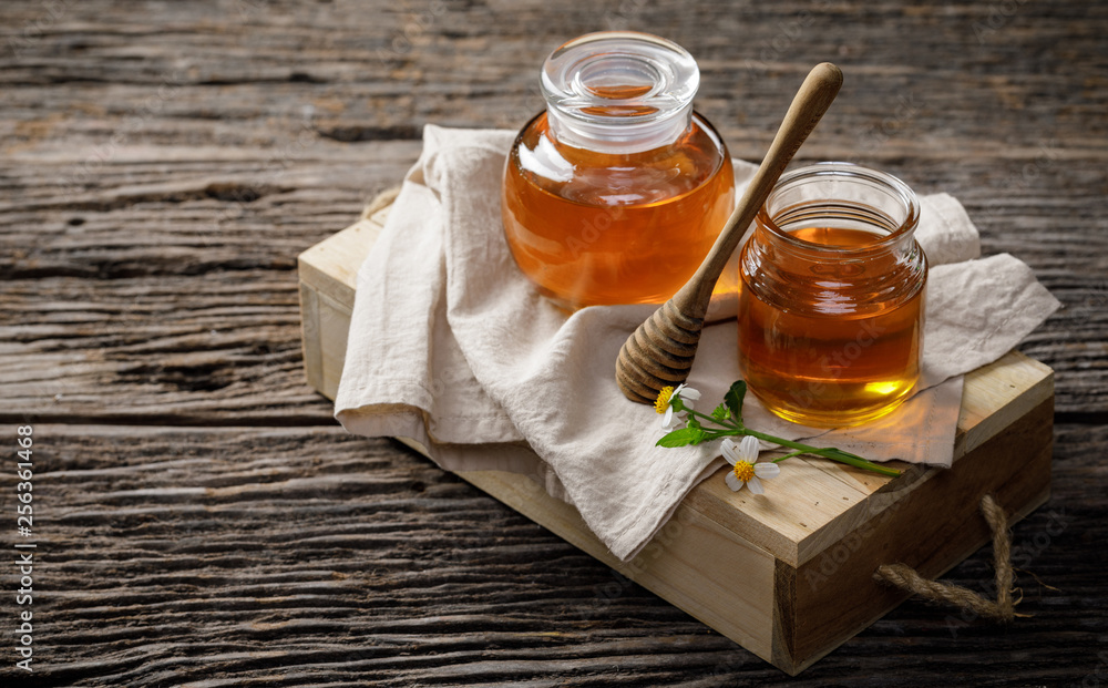 Honey bee in jar with honey dipper and flower on wooden table, bee products by organic natural ingredients concept, copy space for your text Honey bee in jar with honey dipper and flower on wooden table, bee products by organic natural ingredients concept, copy space for your text