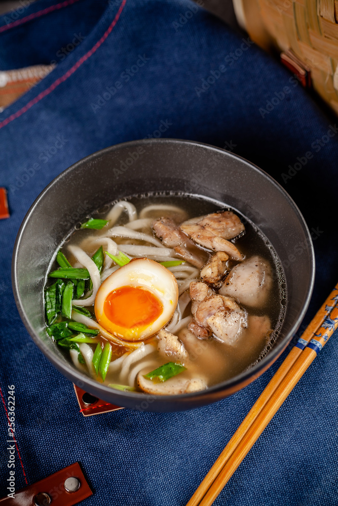 Pan-Asian cuisine concept. Japanese Ramen Soup with Chinese Noodles, Egg, Chicken and Green Onions. Serving dishes in the restaurant in the bowl. Background image. copy space
