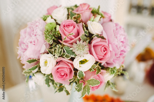 bouquet of peonies and roses in a vase on a served table